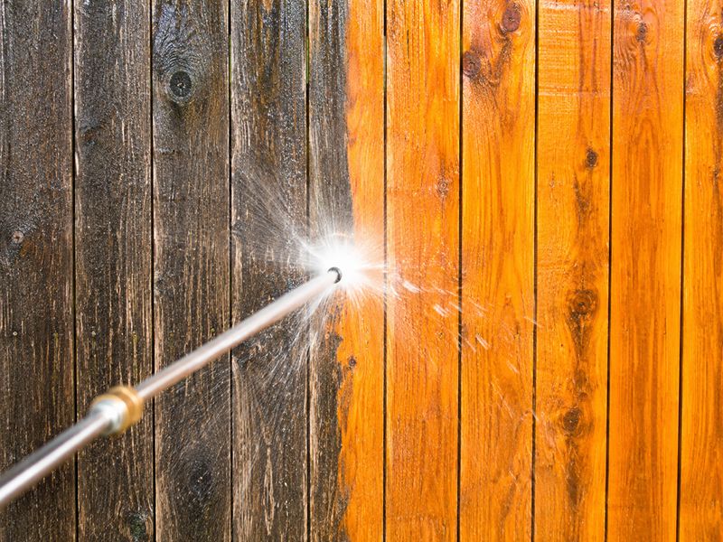 Before and after fence power washing on a weathered wood fence in Oklahoma City