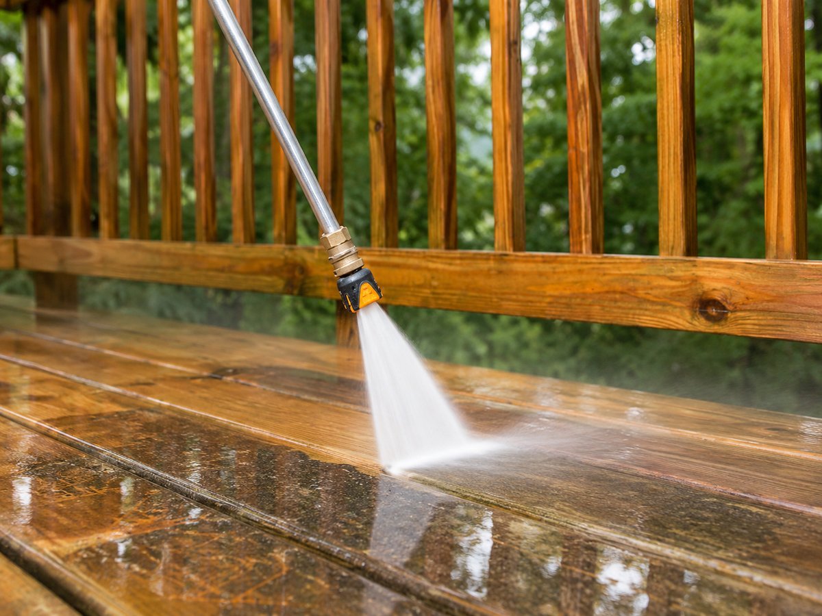 KJ Power Washing technician cleaning a wooden deck in OKC with pressure washer